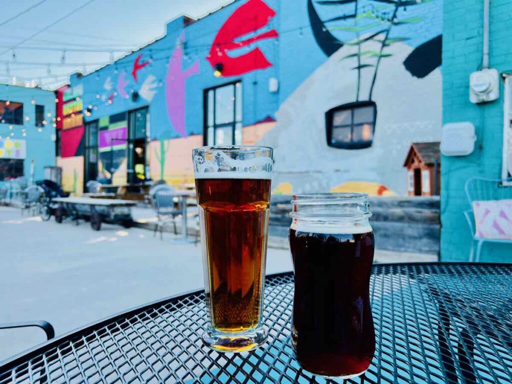 Two craft beers and colorful murals on the back patio at Golden Cactus Brewing, part of Virginia's Blue Ridge Cheers Trail in downtown Roanoke