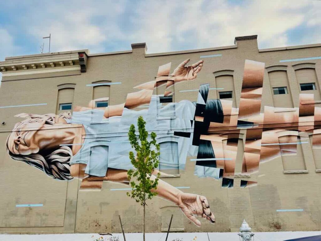 A painting of a woman stretches across a block-long building in the Float Mural on Broad St in Richmond Virginia